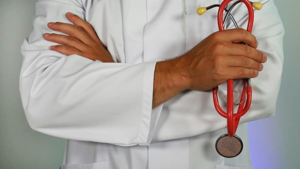 A doctor wearing a white lab coat holding a stethoscope.